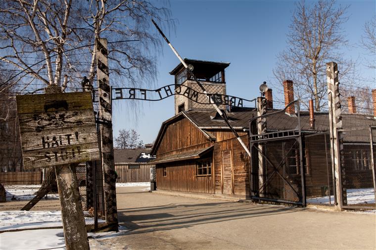 Nus e acorrentados no portão de Auschwitz