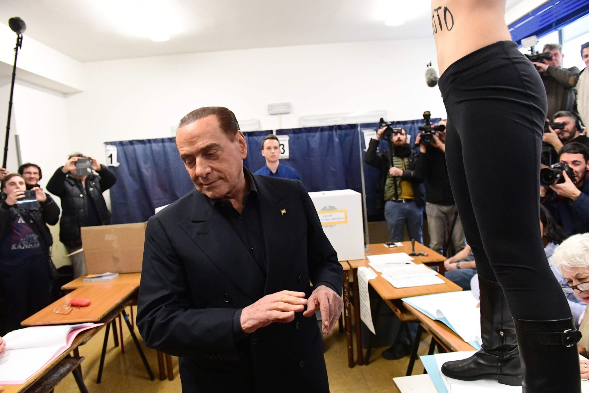 Itália. Berlusconi surpreendido por mulher seminua na altura em que ia votar | VÍDEO